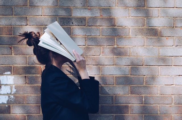 woman covering her face with a white book