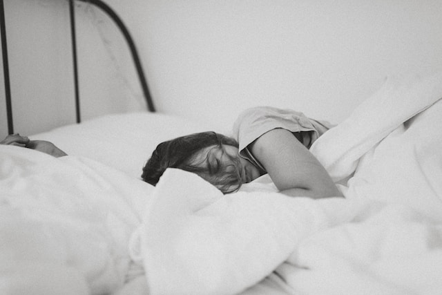 black and white photo of a young woman sleeping in bed